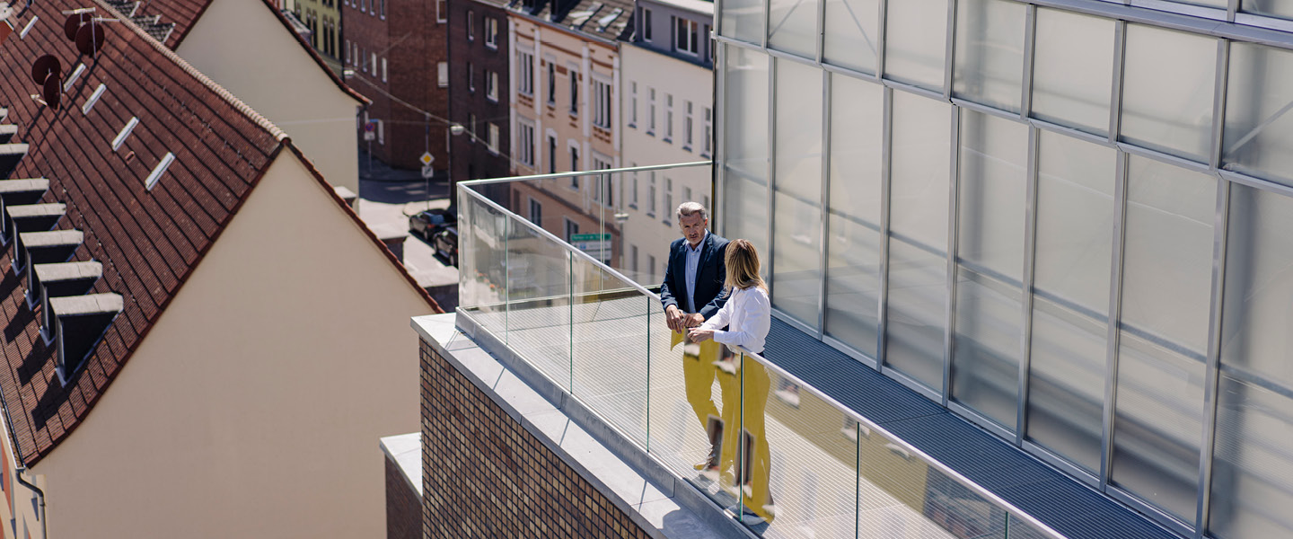 Man and woman talking on balcony with a view