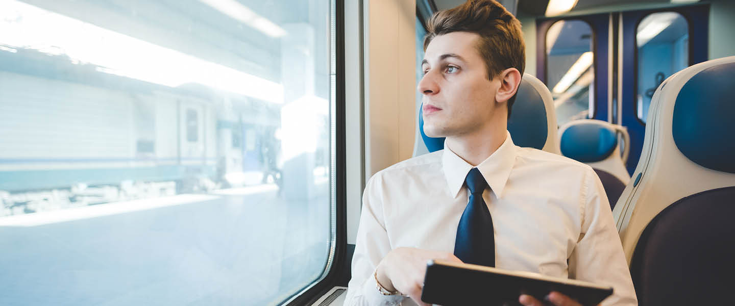 portrait of young businessman commuting using laptop