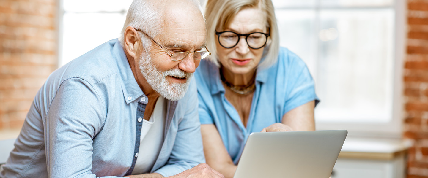 Older man and woman behind laptop