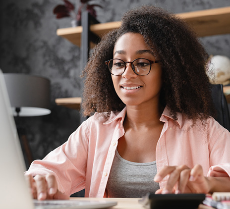 businesswoman counting funds in front of laptop