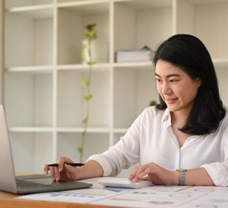 focused asian woman employee using calculator and laptop