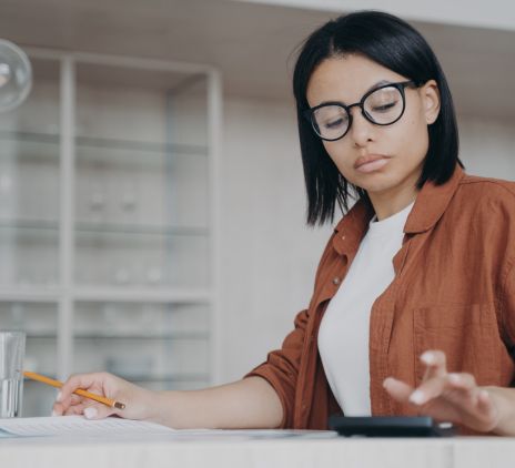 focused female in glasses counting expenses on calculator